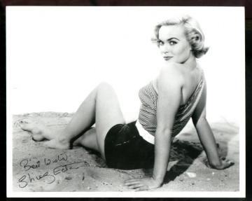 shirley_eaton_sitting_on_sand_looking_over_shoulder